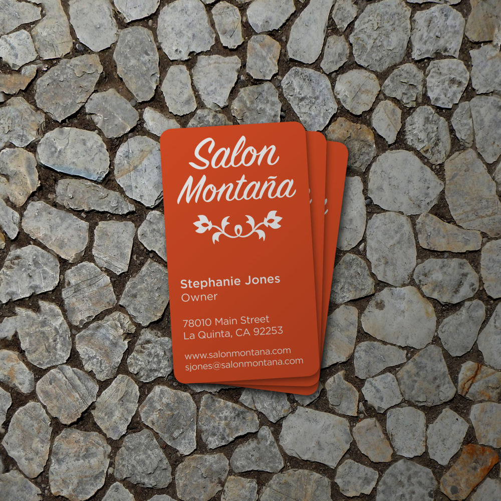 Business cards for Salon Montana placed on a cobblestone surface.