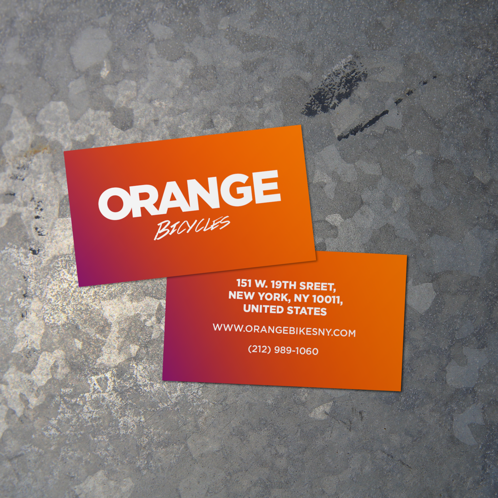 Two business cards for Orange Bicycles placed on a textured gray surface.