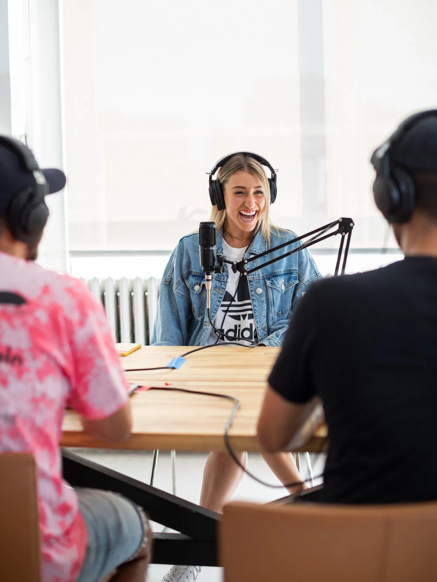 Women recording a podcast in a bright room with large windows.